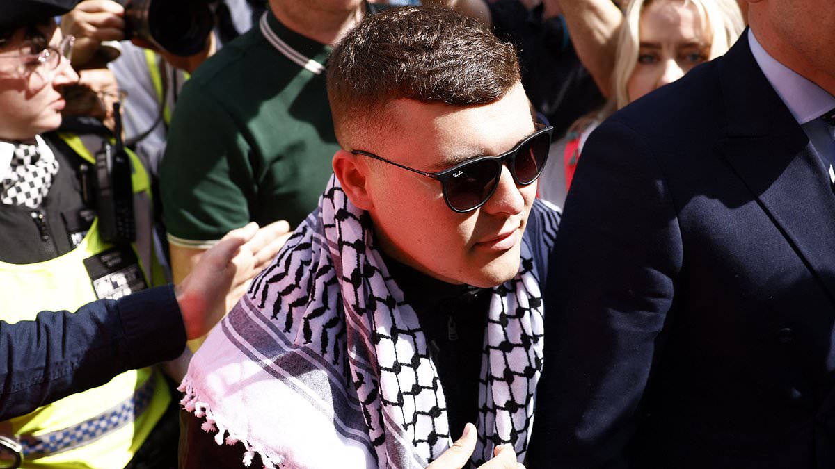 alert-–-kneecap-rapper,-27,-‘who-waved-hezbollah-flag-at-gig’-is-aided-by-an-irish-language-interpreter-as-he-appears-in-court-to-face-terror-charge
